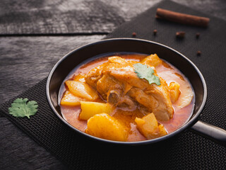 Massaman curry with chicken and potatoes in pan on wooden background. Thai Food