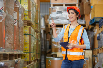 factory worker holding a tablet and looking at shelf in warehouse storage