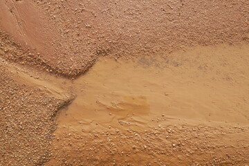 Close-up of earthy and muddy puddle on wet dirt road - obrazy, fototapety, plakaty