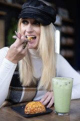 Woman sitting in coffee shop eating scone