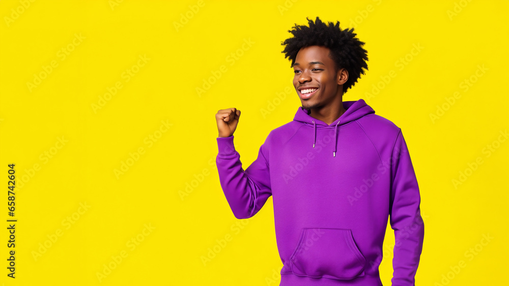 Wall mural african american man smiling, wearing violet sweatshirt on yellow background, with copy space