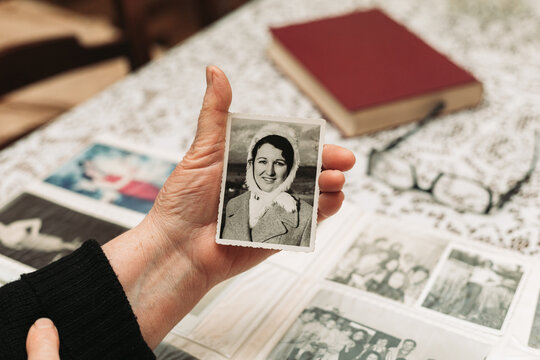 CIRCA 1970: Elderly woman hands holding black and white photo of the young self