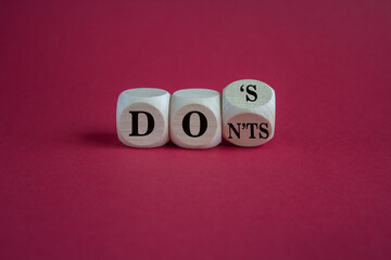 Turned cubes and changes the word don'ts to does. Beautiful red background, copy space. Business, motivational concept.