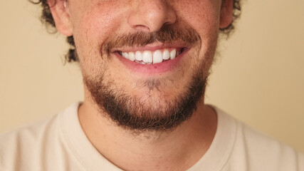 Obraz premium Detailed close-up shot of man's smile in studio on beige background