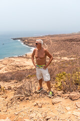 handsome shirtless middle aged man looking at the horizon from a barren promontory