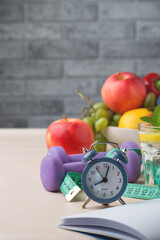 Nutrition, diet, water balance, control of daily routine and exercise. Tape measure for measuring size, dumbbells, clock and many vegetables and fruits in the background..
