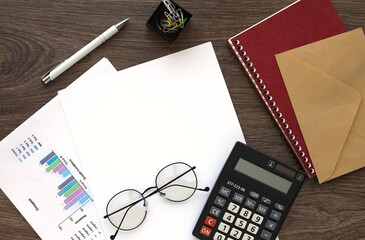 calculator and white countries on a wooden office table on financial charts. Top view with copy space, flat lay.