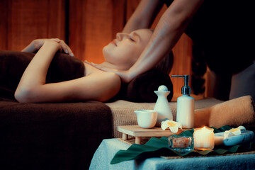 Obraz na płótnie Canvas Aromatherapy massage ambiance or spa salon composition setup with focus decor candles and spa accessories on blurred woman enjoying blissful aroma spa massage in resort or hotel background. Quiescent