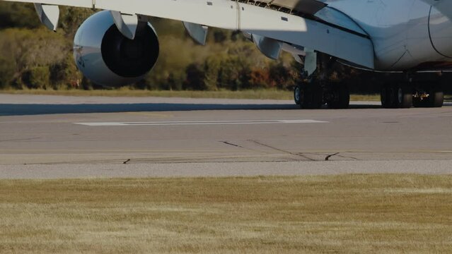 Close-up of a widebody jet taxiing on the airport runway, with its landing gear turning around on the tarmac