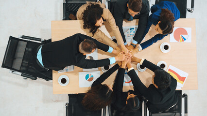 Fototapeta na wymiar Happy business people celebrate teamwork success together with joy at office table shot from top view . Young businessman and businesswoman workers express cheerful victory show unity support . Jivy