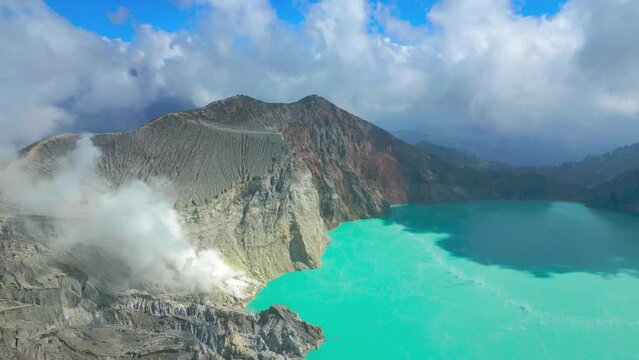 Active volcano Kawah Ijen in the crater with sulfur lake turquoise color and smoke emissions from burning sulfur, East Java, Indonesia. Aerial Drone view 4K.
