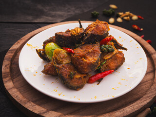 Stir fried catfish with herb and spicy sauce in plate on wooden background. Traditional Thai southern food