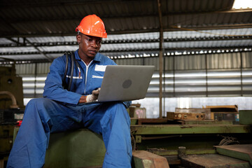 Naklejka na ściany i meble male african workers or technician using laptop computer on machine in the factory