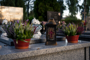 Ornate grave candle with cross motif among heather flowers on a tombstone — Poland, November 1,...