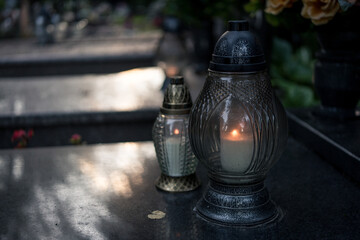 Lit decorative grave candles by a tombstone — Poland, November 1, All Saints’ Day (also known...