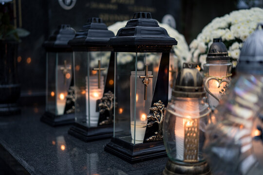 Lit grave candles (grave lanterns) decorating a tombstone at dusk &mdash; Poland, November 1, All Saints&rsquo; Day (also known as All Souls&rsquo; Day / Day of the Dead)