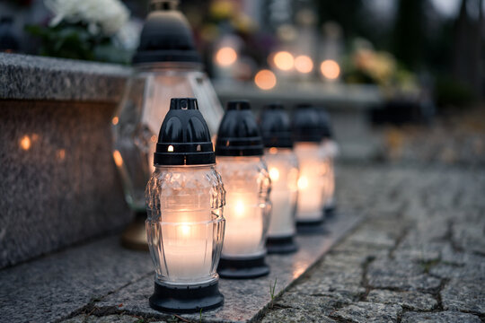 Lit grave candles (grave lanterns) decorating a tombstone at dusk &mdash; Poland, November 1, All Saints&rsquo; Day (also known as All Souls&rsquo; Day / Day of the Dead)