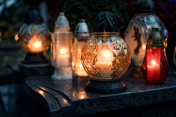 Lit grave candles on a tombstone on a November evening with soft warm candlelight — Poland,...