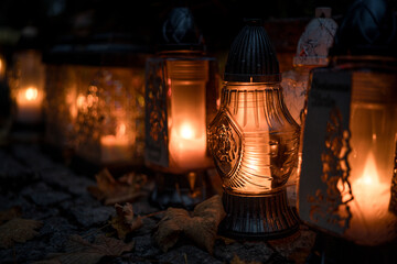 Lit grave candles on a tombstone on a November evening with soft warm candlelight — Poland,...