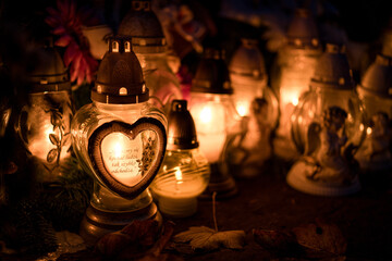 Lit grave candles on a tombstone on a November evening with soft warm candlelight — Poland,...