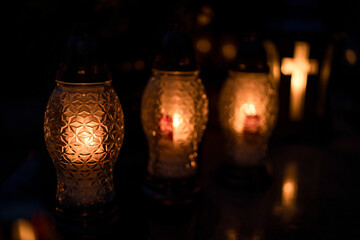 Lit grave candles on a tombstone on a November evening with soft warm candlelight — Poland,...