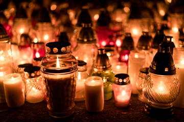 Many lit grave candles at the base of a cemetery monument — Poland, November 1, All Saints’ Day...