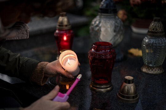 Hand lighting and placing a grave candle at a tombstone, close-up, Poland, November 1 - All Saints' Day (also known as All Souls' Day, Day of the Dead)