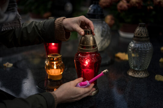 Hand lighting and placing a grave candle at a tombstone, close-up, Poland, November 1 - All Saints' Day (also known as All Souls' Day, Day of the Dead)