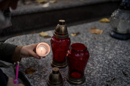 Hand lighting and placing a grave candle at a tombstone, close-up, Poland, November 1 - All Saints' Day (also known as All Souls' Day, Day of the Dead)