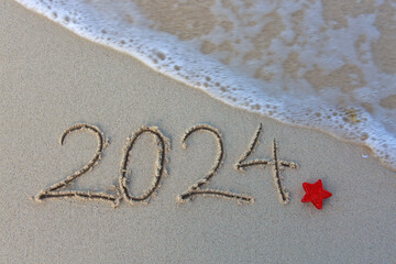Fototapeta na wymiar New Year 2024 handwritten in the white sand surface.