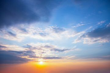 Naklejka na ściany i meble Sunrise with sun rays sunlight in clouds against bright blue sky