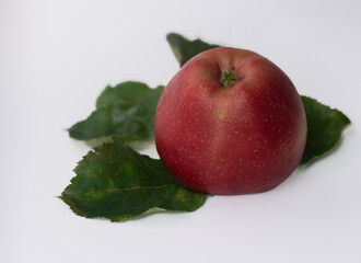 red apple and green leaves on white background