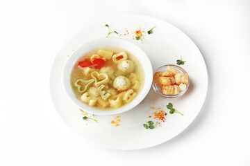 Children's menu. Soup with chicken meatballs and vermicelli. Crackers with soup. Flat lay. Copy space. Isolated object.