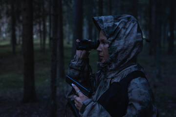 A girl hunting with a night vision device at dusk. - obrazy, fototapety, plakaty