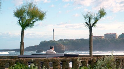 Biarritz beach with La Roche Percée rock and lighthouse in the background. A Rafale airplane is passing by. - 658802628