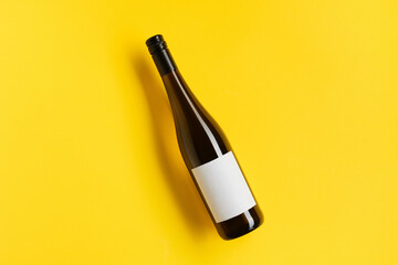 Wine bottle with blank label. Red wine on yellow background with copy space. - obrazy, fototapety, plakaty