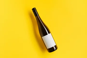 Fotobehang Wine bottle with blank label. Red wine on yellow background with copy space. © Darya Lavinskaya