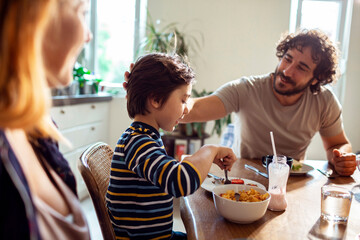 Young family having breakfast together in the morning in their kitchen at home