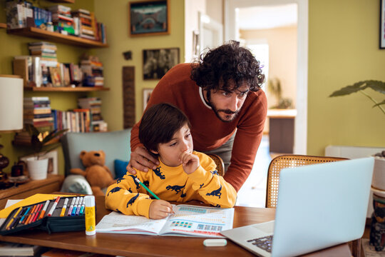Young father helping his son with the homework at home