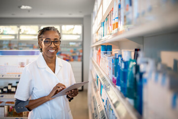 Portrait of a smiling female pharmacist going over inventory in a pharmacy