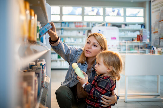 Young woman shopping for supplies with her daughter at the pharmacy - Powered by Adobe