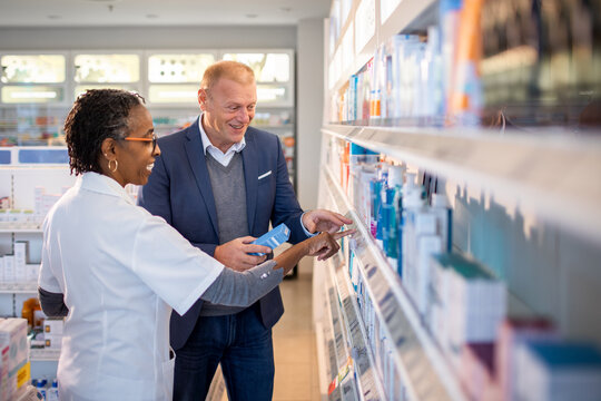 Senior female pharmacist offering advice to a customer about medication in a pharmacy