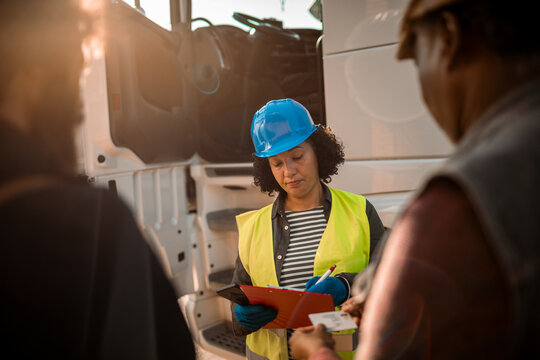 Diverse truck drives signing a contract for a shipment at the parking lot