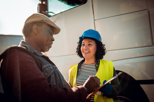 Mature truck driver signing a contract for a shipment at the parking lot