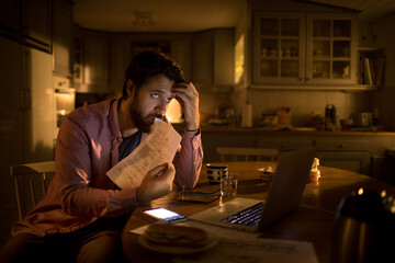 Young man contemplating his financial crisis in the kitchen of his home