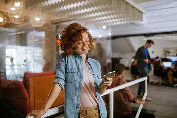 Young Caucasian woman using a smartphone in the office of a startup company