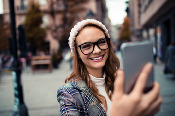 Young attractive woman using her smartphone while shopping in the city