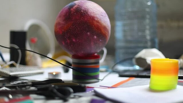A balloon in the shape of a planet. Planet light fixture in the room. A mess on the floor. Just objects.