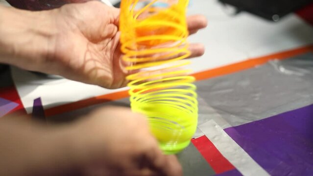 Игрушка в руках. Пружина из пластика. Веселое настроение. Яркий предмет. 