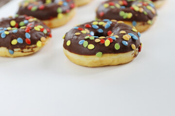 Set of Brown chocolate donut decorated with smarties isolated on white background side view. Fried dough confection, dessert food, sweet snack with chocolate glazing and candies. Selective focus